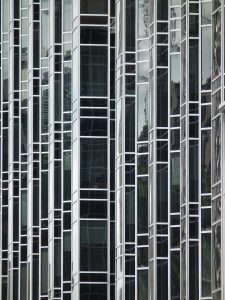 A close-up view of a modern glass building facade featuring vertical reflective panels and metal framing.