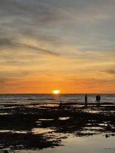 A picturesque sunset over the ocean, with a vibrant orange and yellow sky. 
