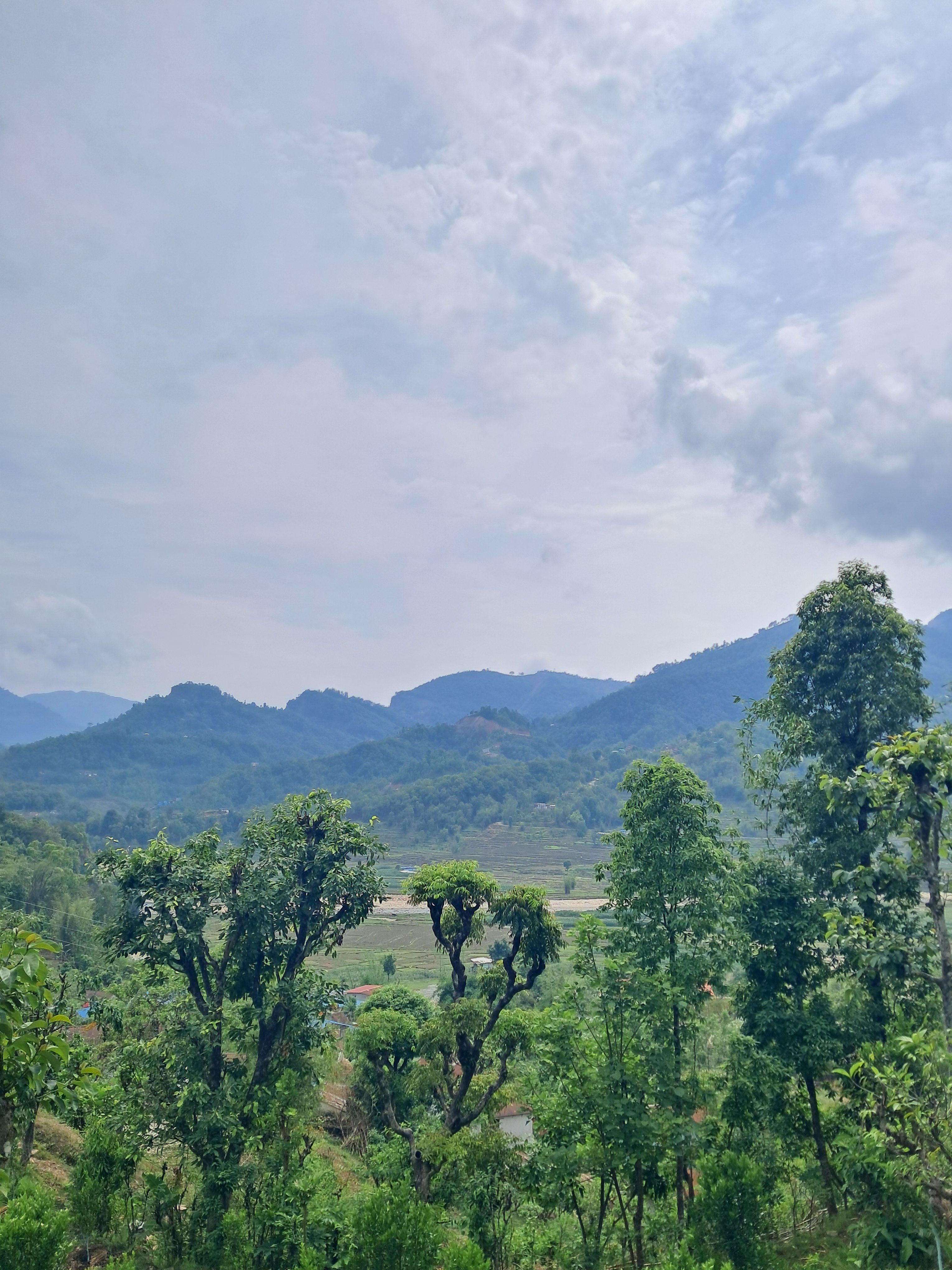 A scenic view of rolling green hills and mountains under a partly cloudy sky.