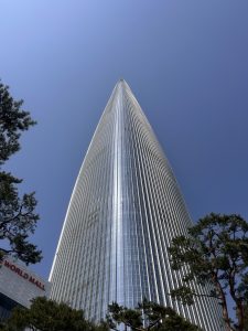 A tall, modern skyscraper reaching into a clear blue sky, with a pointed top and a sleek glass facade