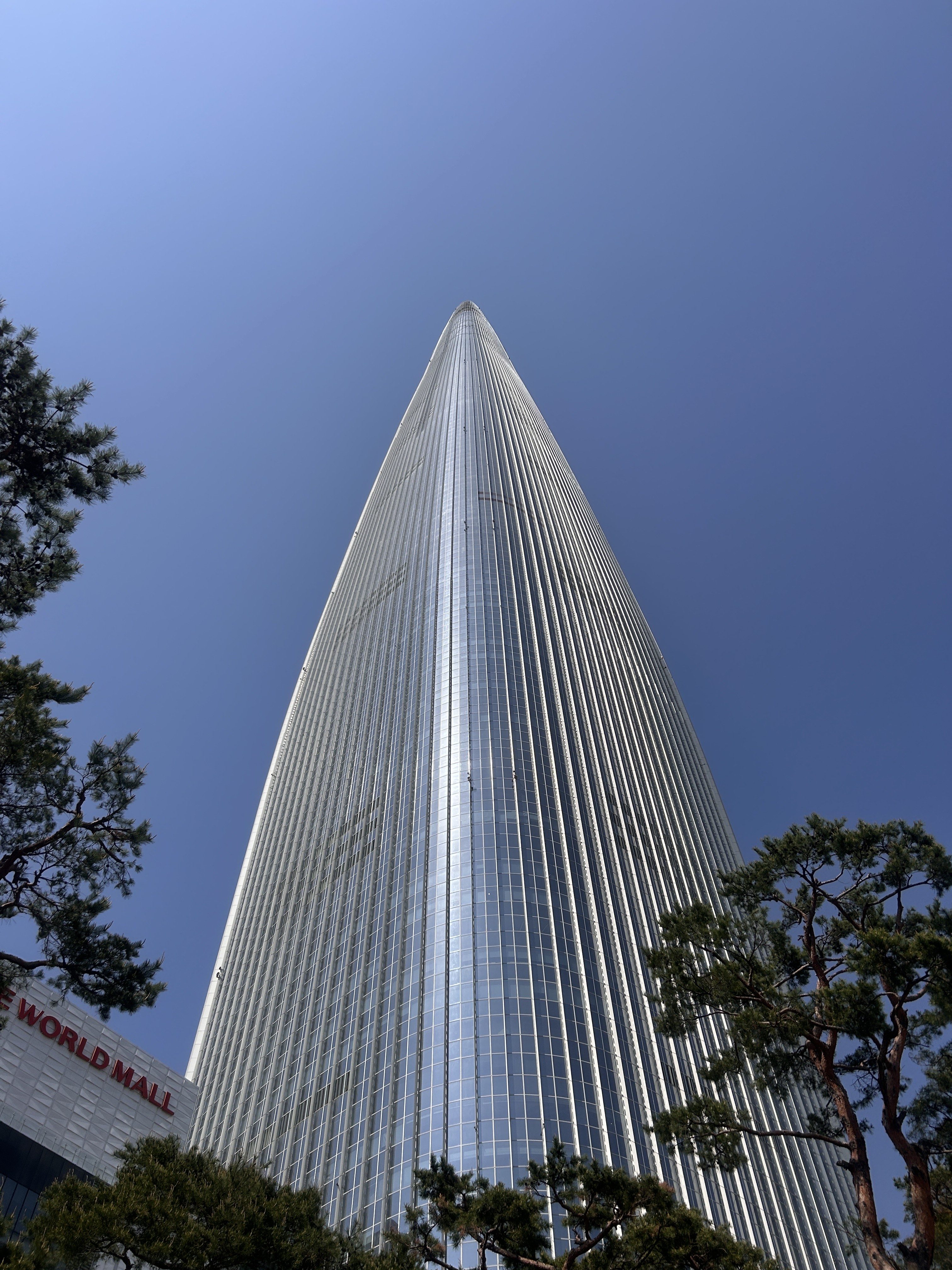 A tall, modern skyscraper reaching into a clear blue sky, with a pointed top and a sleek glass facade