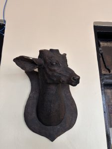 A mounted wooden sculpture of a deer's head is displayed on a wall.