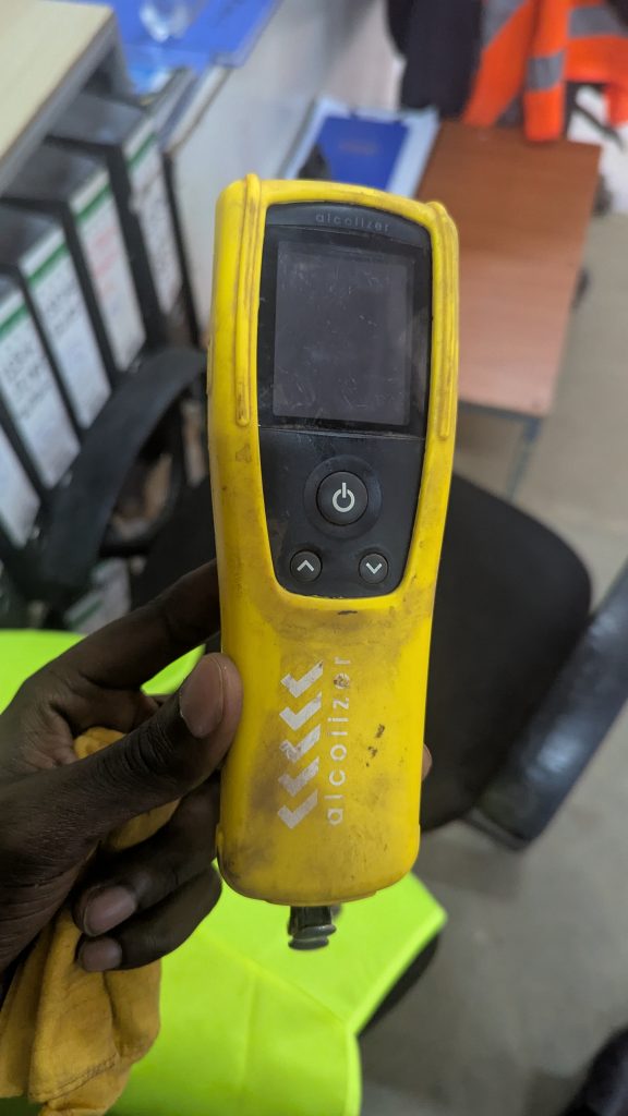 A person is holding a yellow alcohol breathalyzer device.