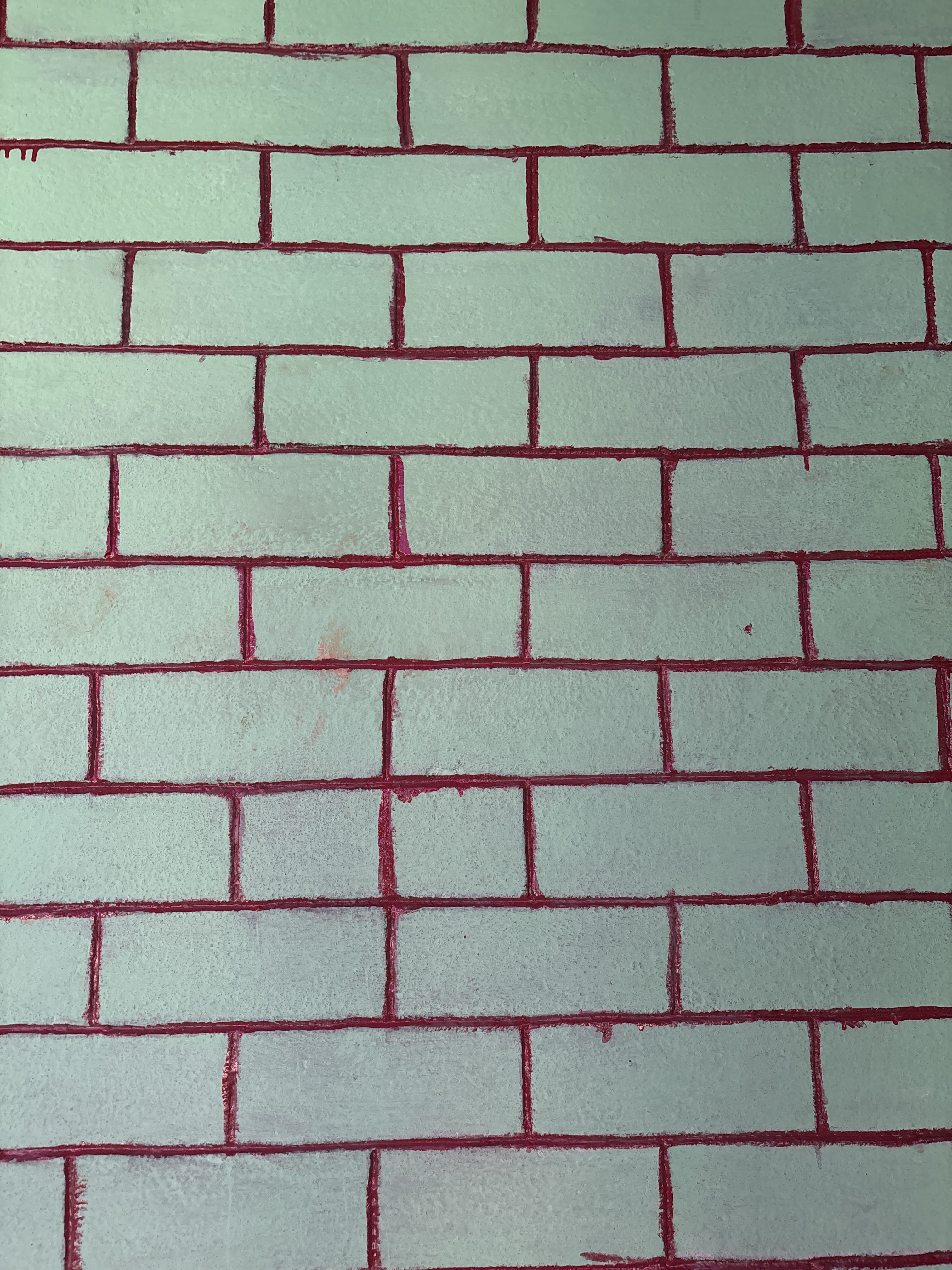 A textured wall featuring a pattern of light green bricks outlined in red mortar.