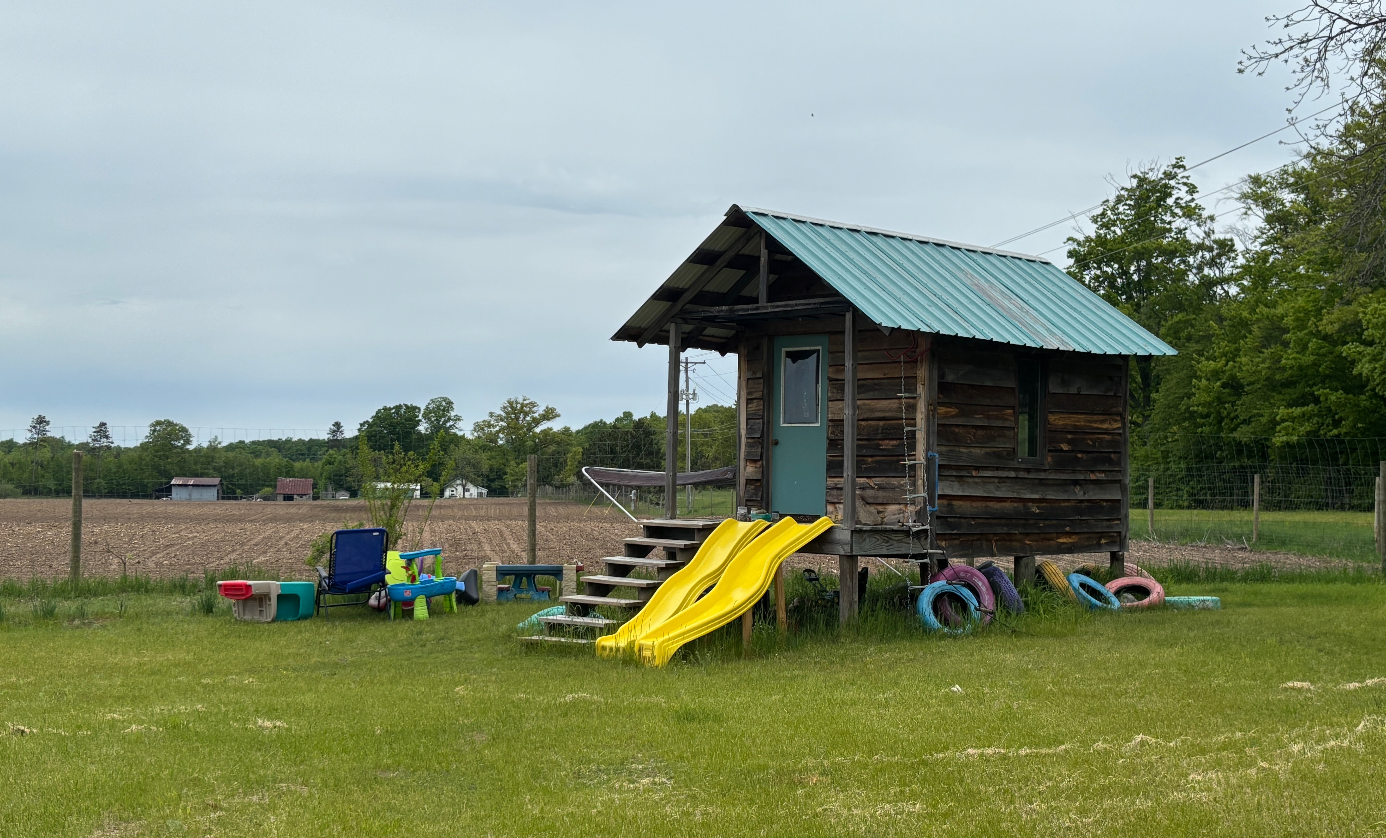 A small building on silts about a meter off the ground. It's configured for children's play, with slides from the front porch, colorful tires around it, and toys around it.