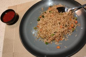 A plate of Vegetable Fried Rice served with a side of sauce.
