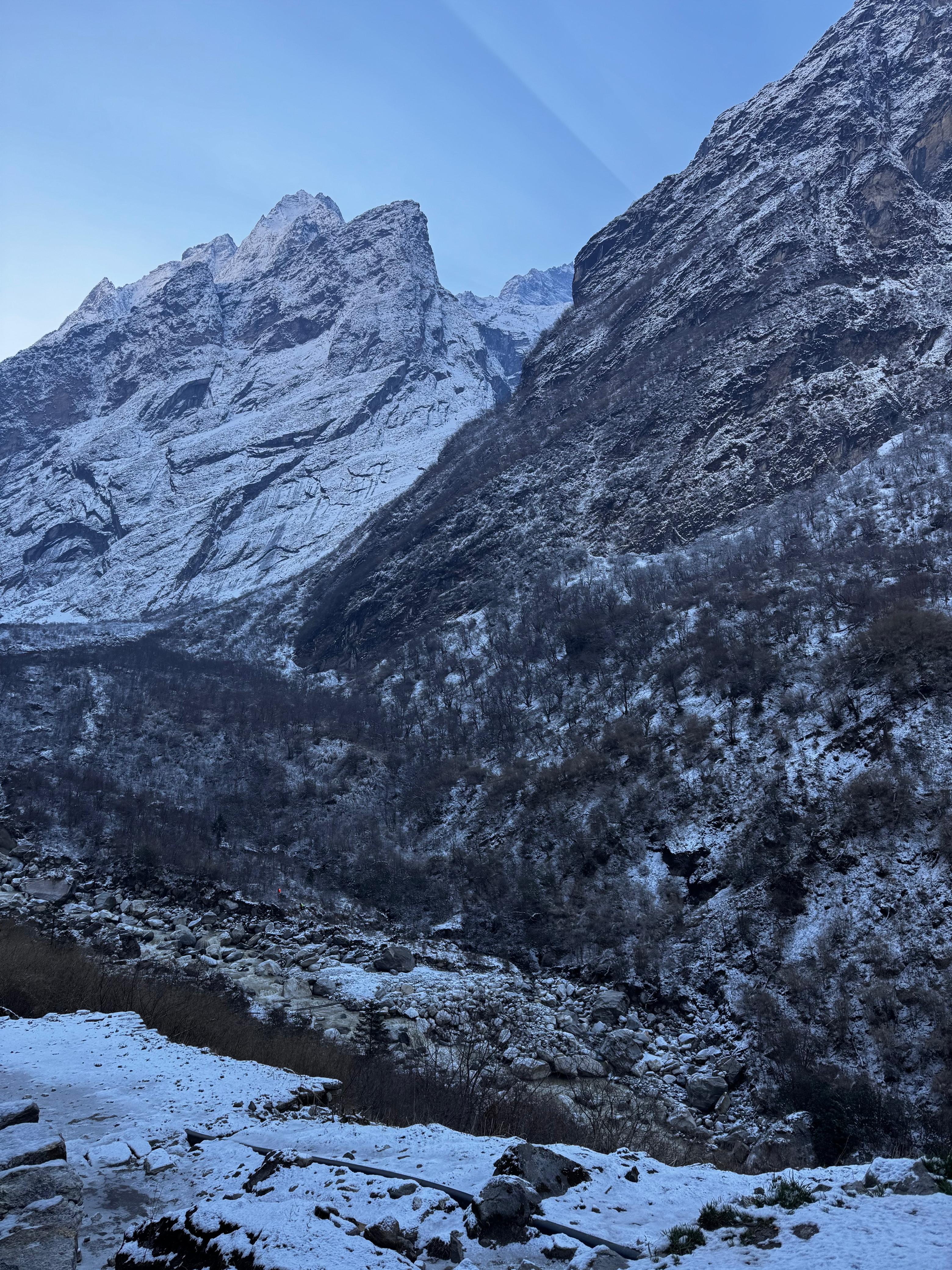 A snowy mountainous landscape during the daytime, featuring towering peaks covered in white snow under a clear blue sky.