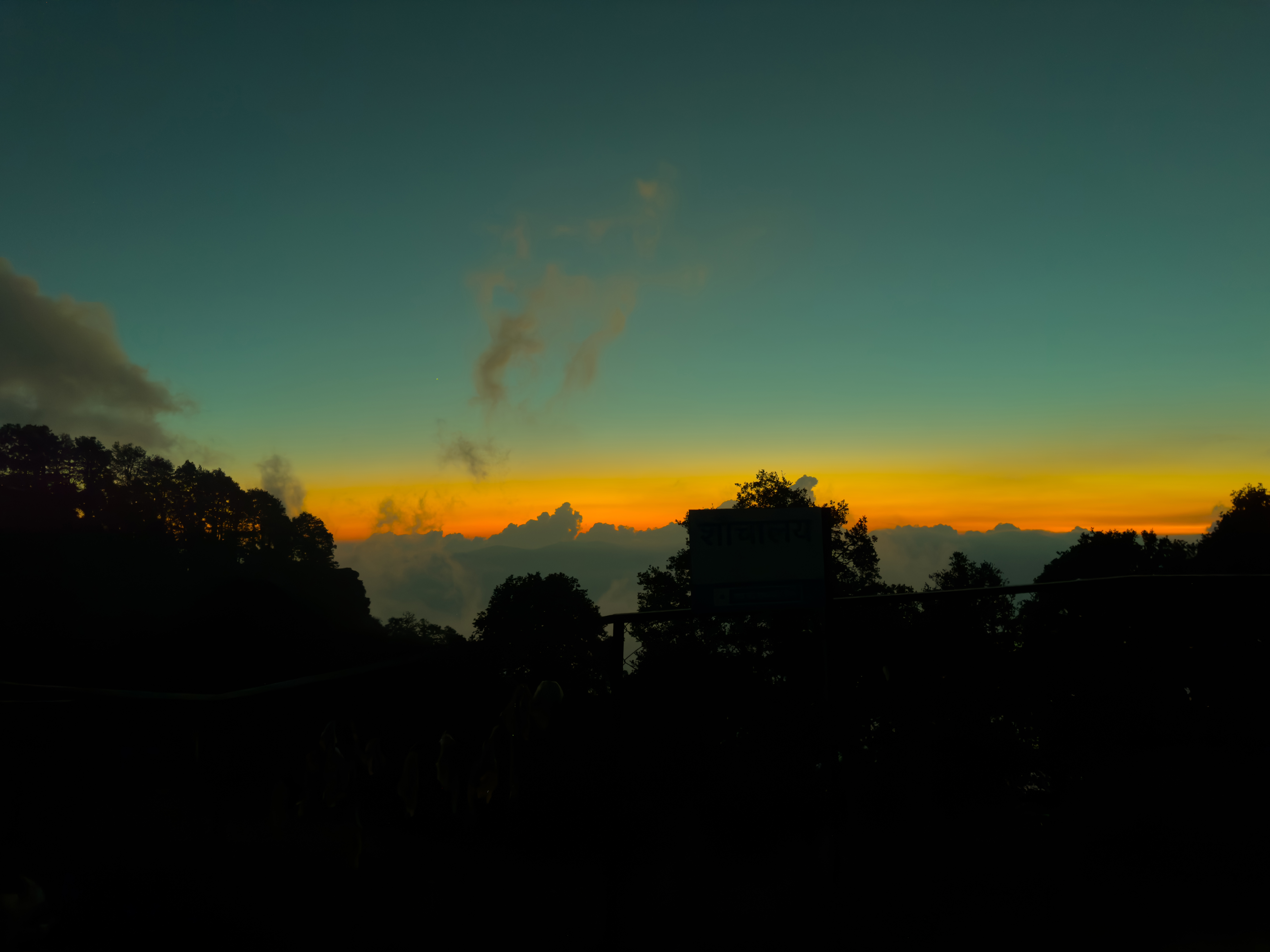 A scenic view of a sunset with vibrant orange and yellow hues blending into a deep blue sky.