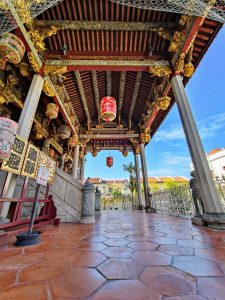 A beautifully preserved corridor at Khoo Kongsi Clan Temple in George Town, Penang, Malaysia showcases ornate wooden ceilings, red lanterns, gold carvings, and tiled flooring — all reflecting the grandeur of traditional Chinese heritage architecture.
