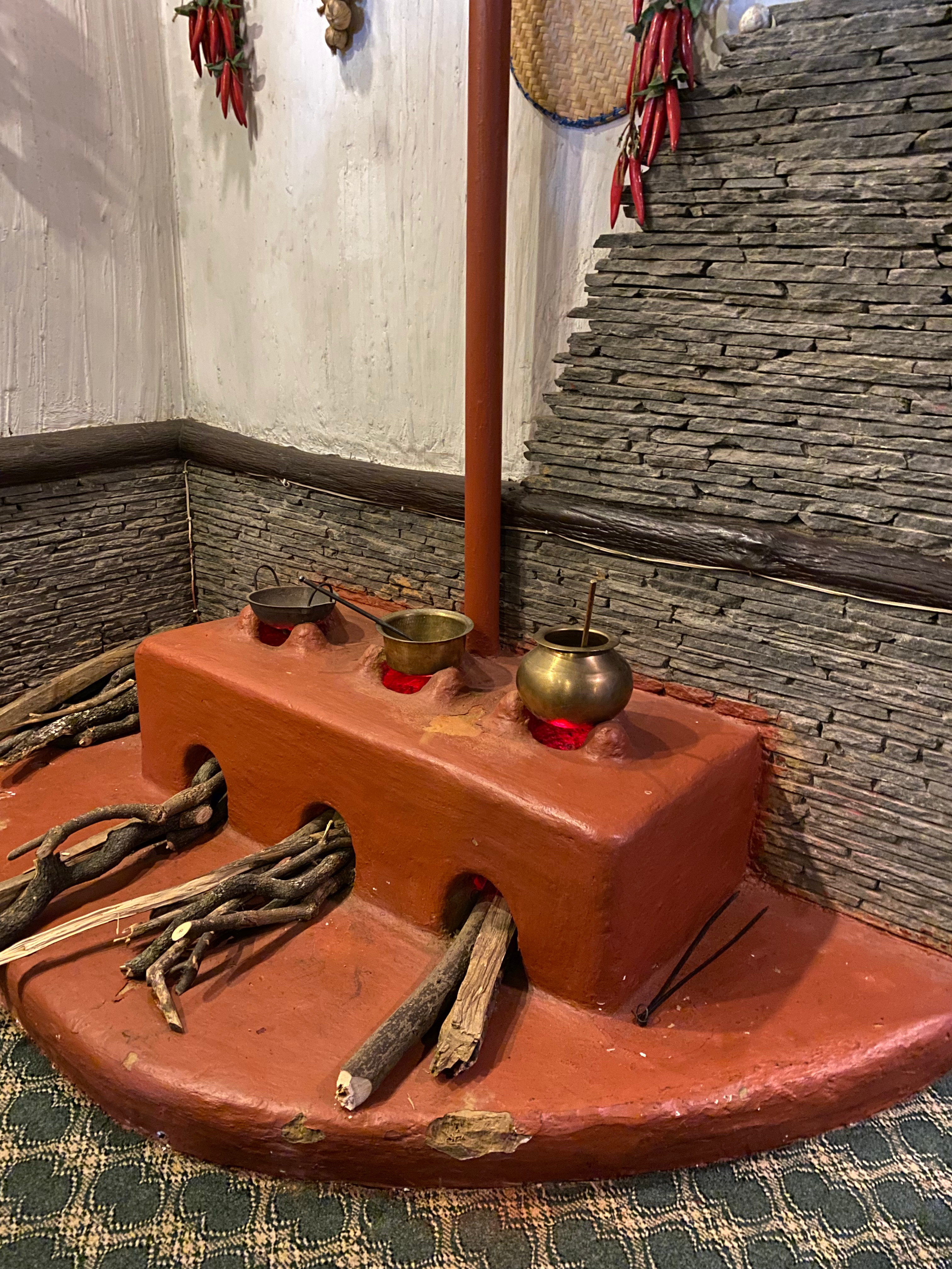 A traditional cooking area featuring a clay stove with three round openings at the front.