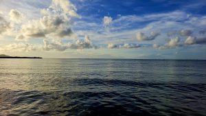 A serene seascape featuring calm waters reflecting the light of the sky.