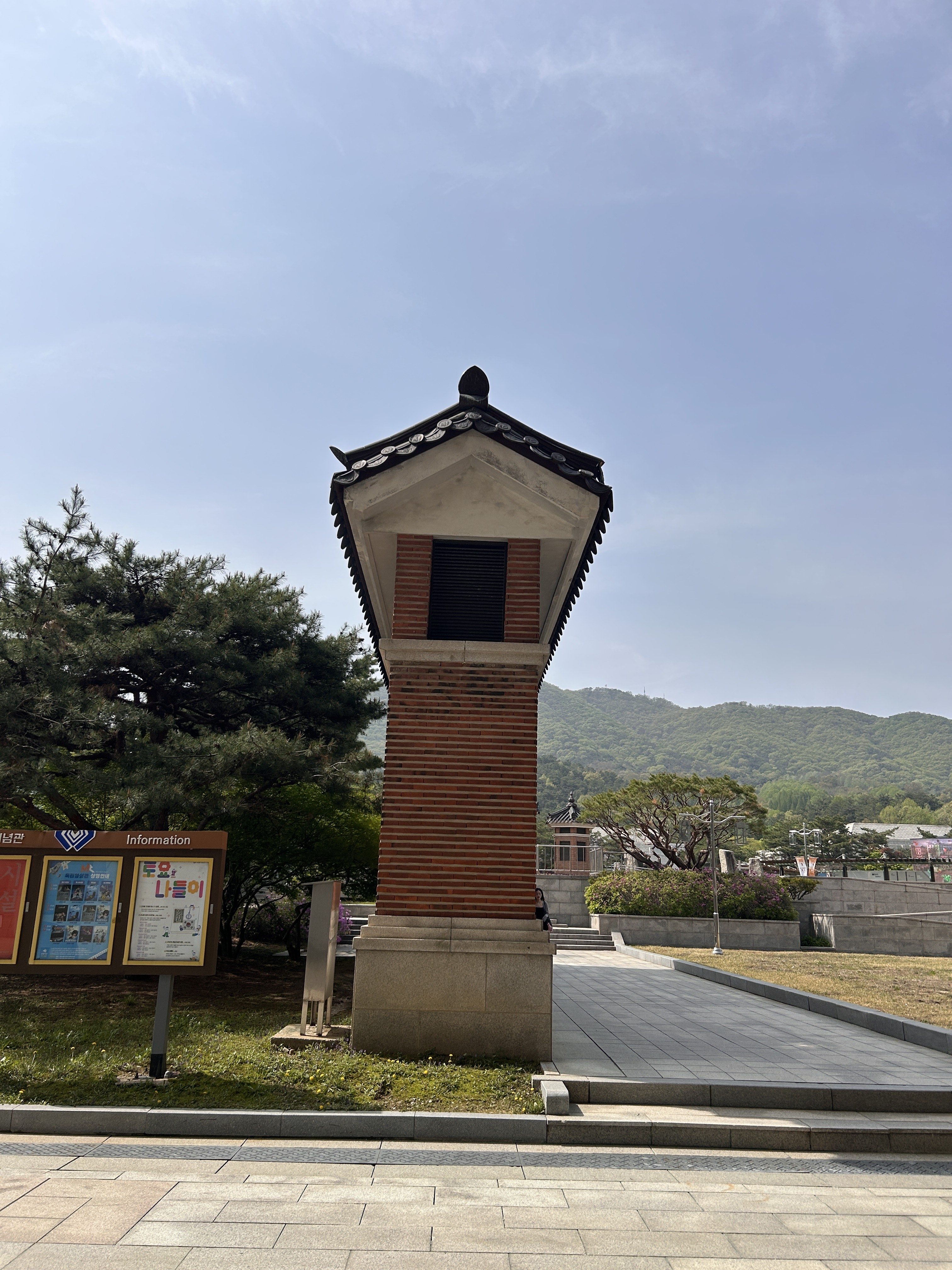 A tall, traditional-style structure with a distinctive tiled roof and brick detailing, standing beside a pathway.