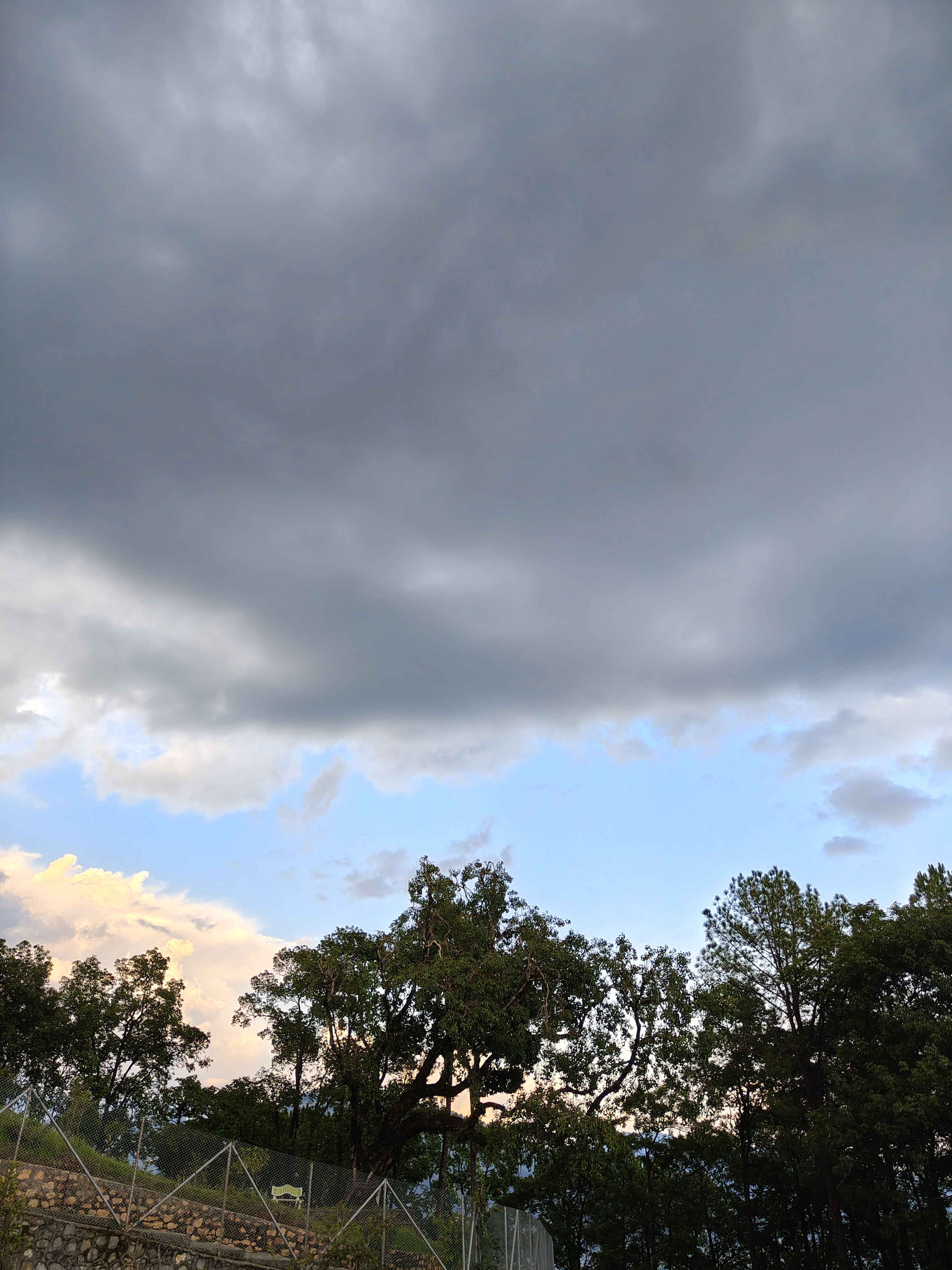 A cloudy sky dominates the upper portion of the image, with dark gray clouds contrasting against lighter blue and pink hues near the horizon.