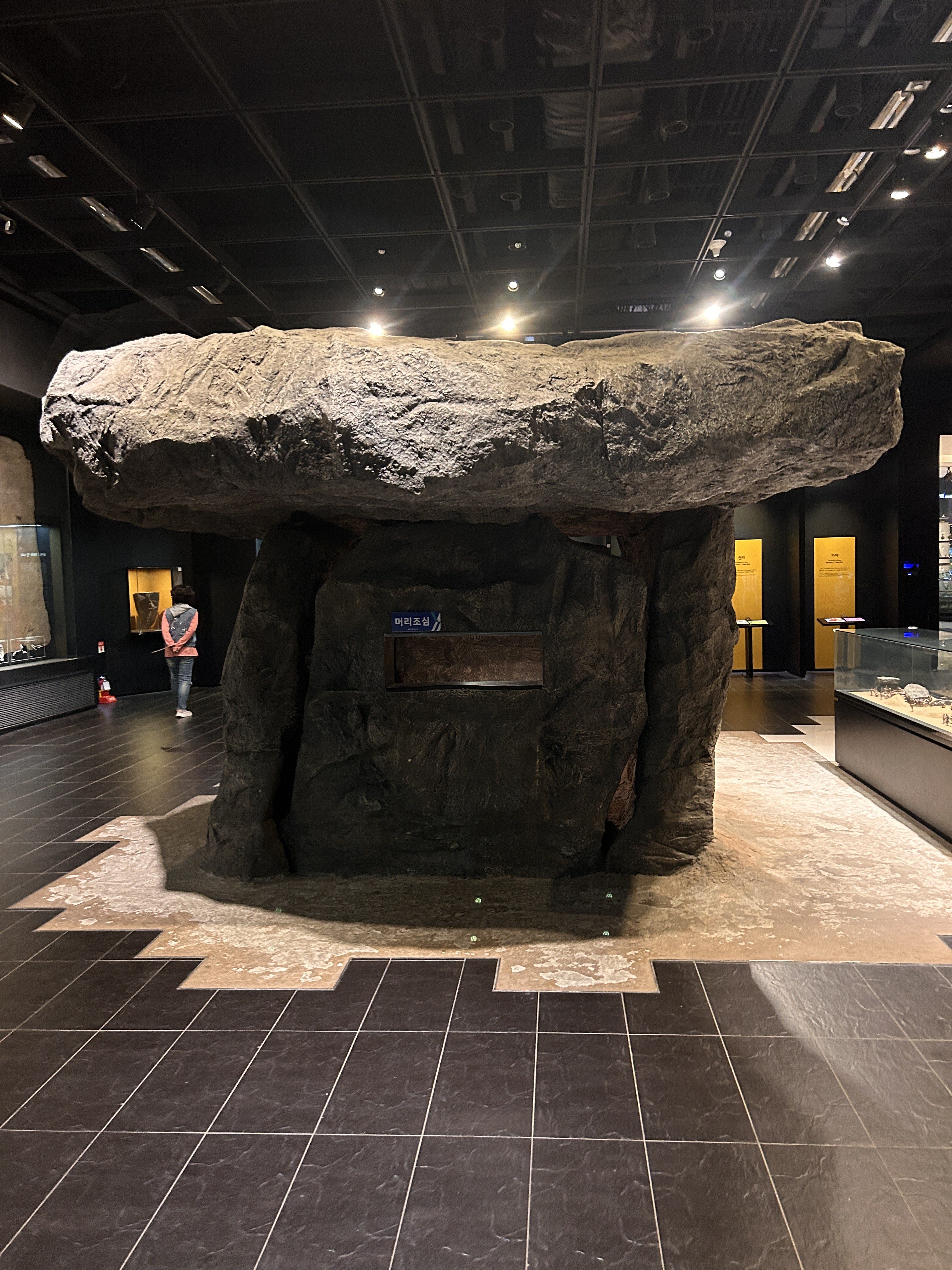 A large prehistoric stone structure resembling a dolmen is displayed in a museum setting