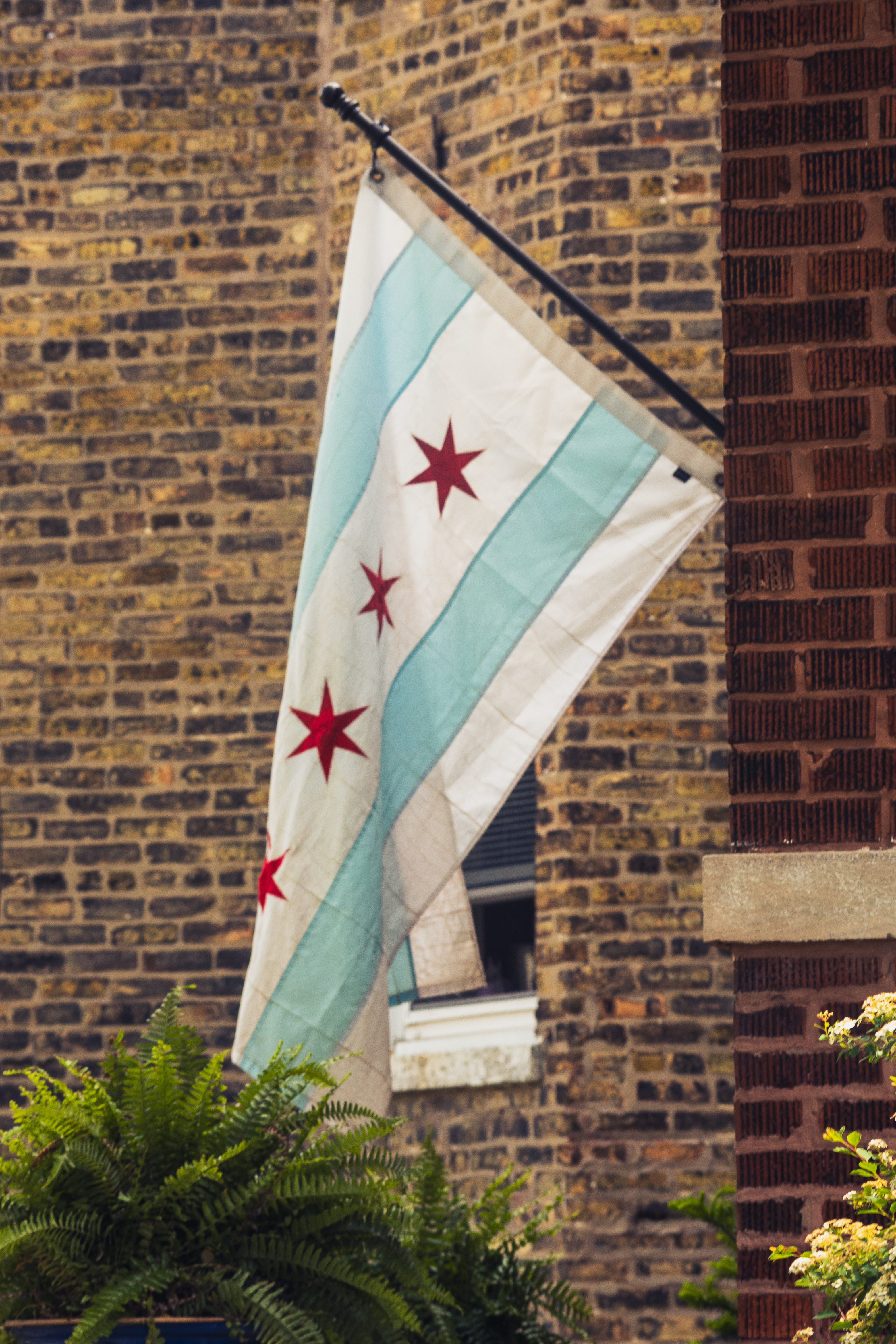 The Chicago flag hangs from the front of a brick building with another brick building in the background