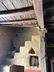 An interior view of a rustic room featuring traditional mud walls and a wooden ceiling. 