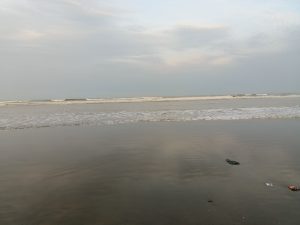 A tranquil beach scene at dusk, featuring gentle waves lapping at the shore.
