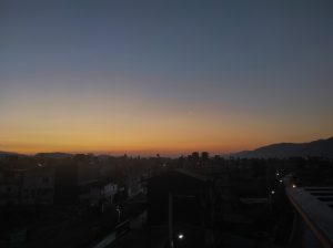 A serene dusk scene depicting a city skyline with scattered buildings. 