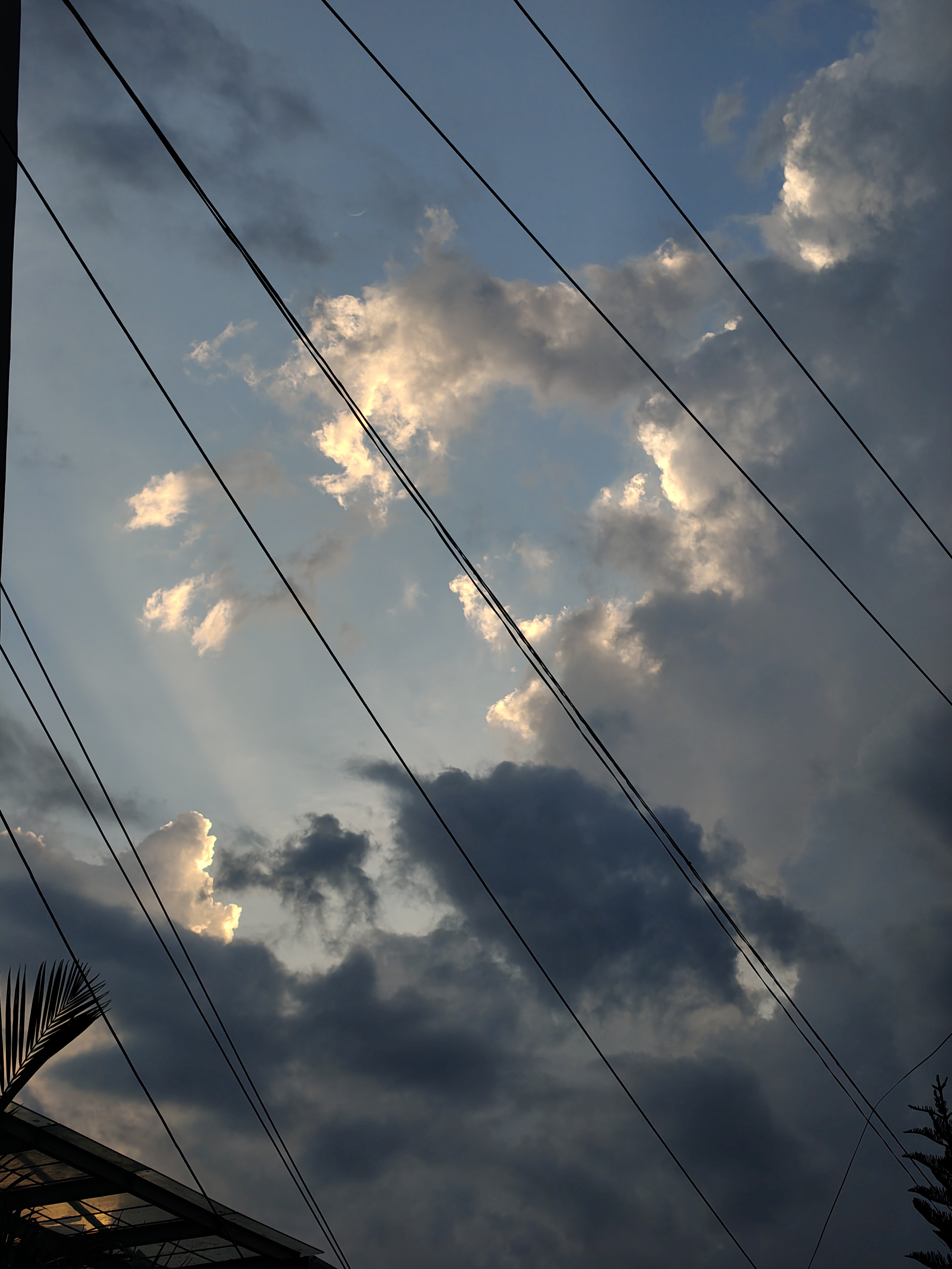 A dramatic sky filled with varying shades of clouds, ranging from light gray to dark, set against a blue background.