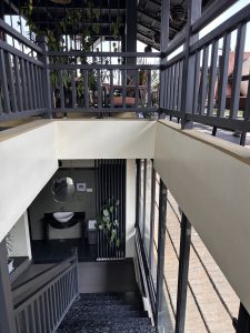 A staircase with dark stone steps leads down to a landing area. The walls are painted in light colors, and there are modern railings made of wood.