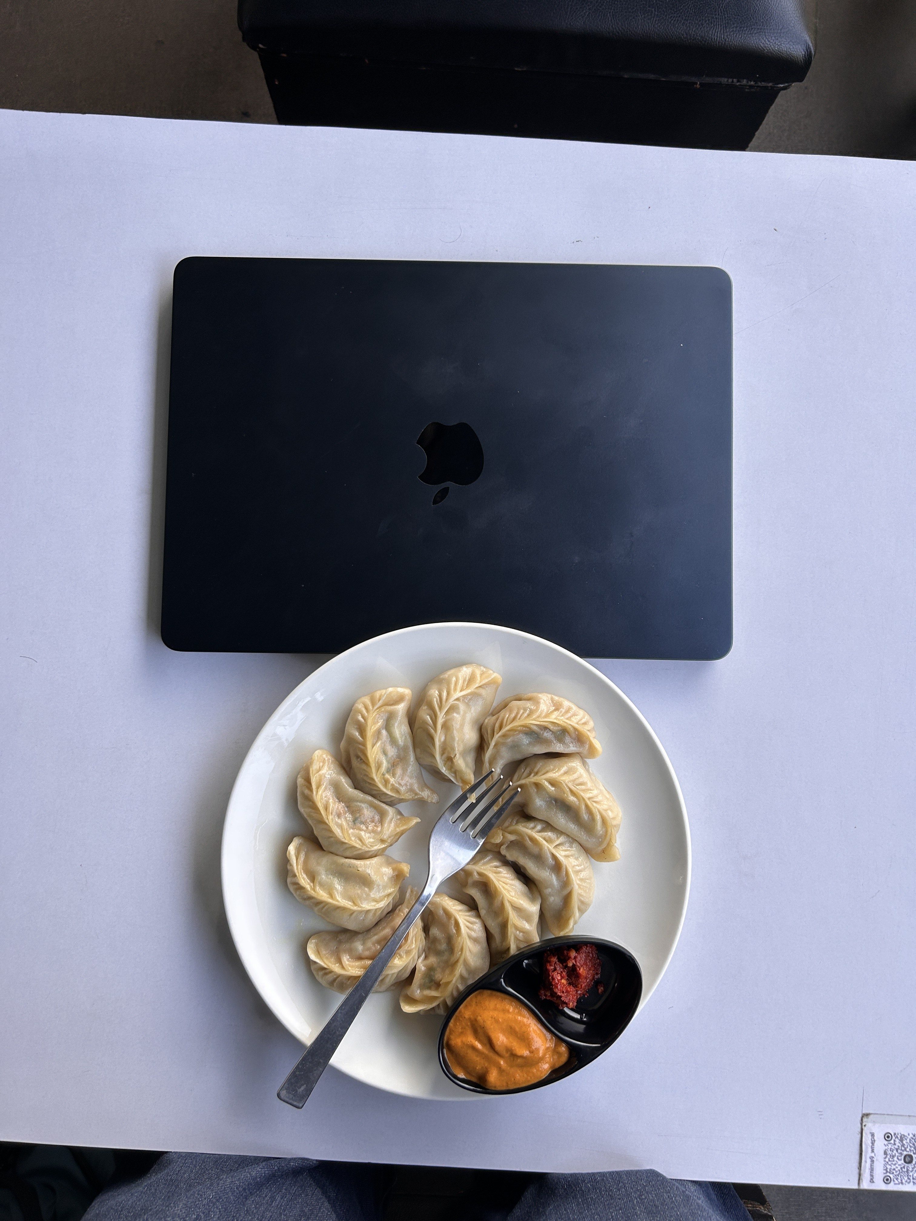 A plate of dumplings arranged in a circular pattern sits on a white table.