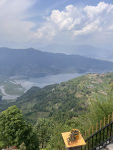 A long view from a height, probably a mountain, looking across a broad valley with a lake in the bottom. There are mountains on the horizon. The hills below the vanatage point are terraces for fields and housing.