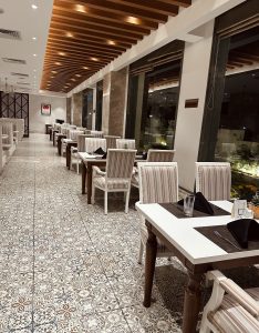 A stylish restaurant interior with a long row of tables and chairs featuring striped upholstery.