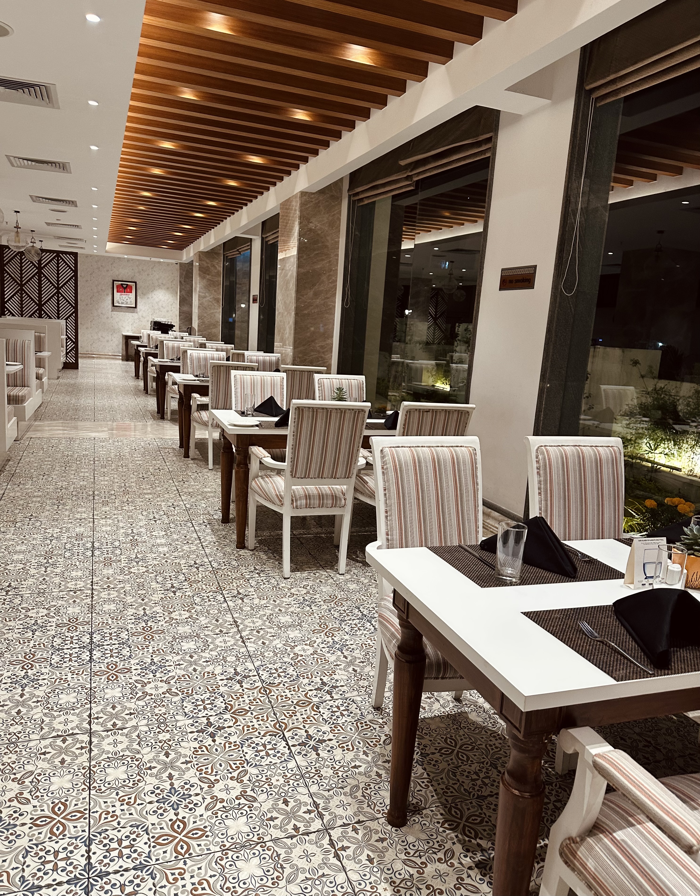 A stylish restaurant interior with a long row of tables and chairs featuring striped upholstery.