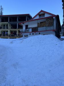 A snowy landscape featuring two buildings surrounded by a thick layer of snow.
