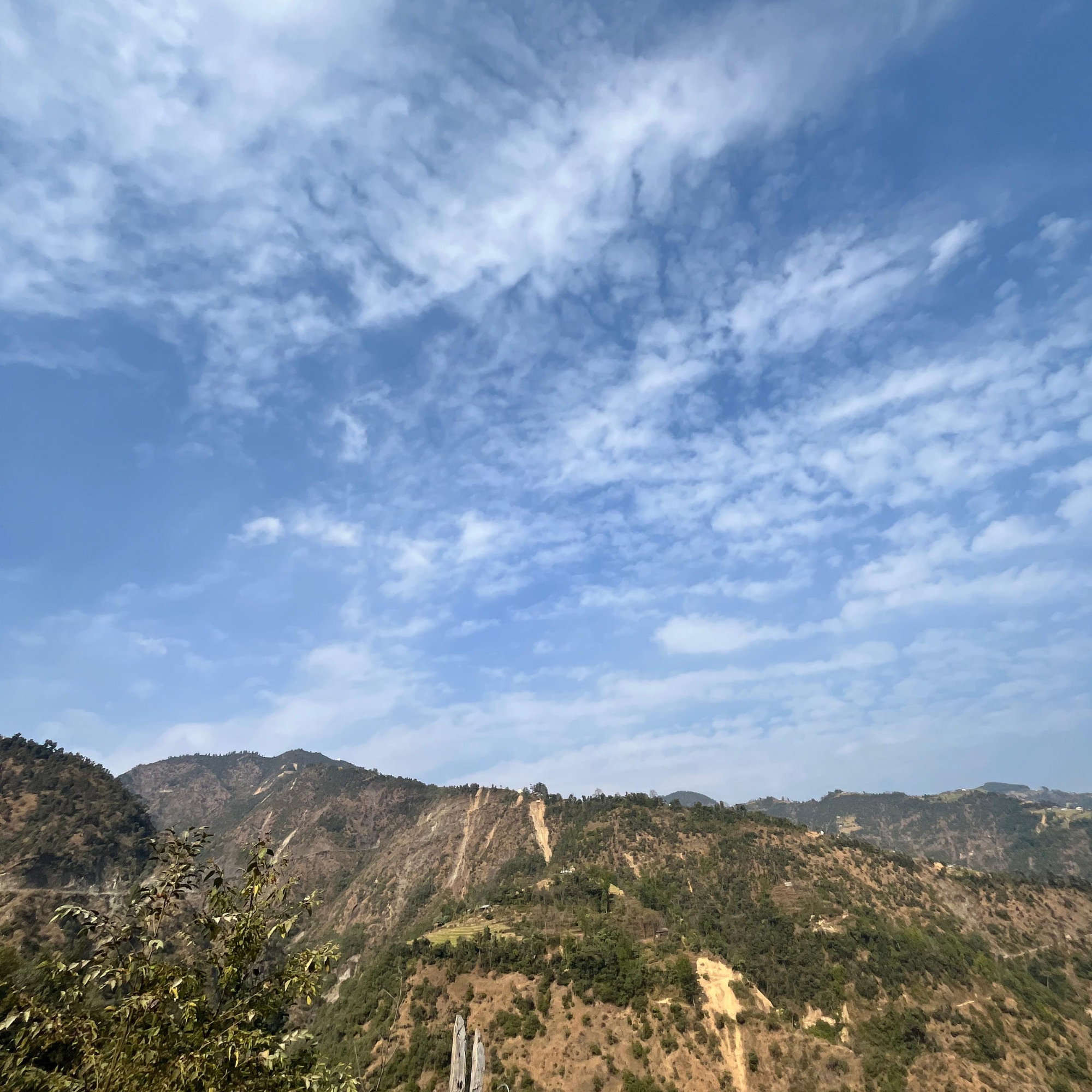 A scenic view of rolling hills under a blue sky with scattered clouds.