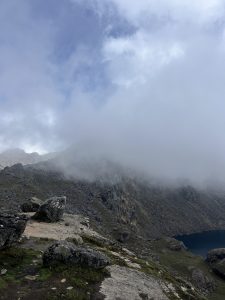 A mountain landscape featuring rocky terrain and patches of grass, under a cloudy sky.