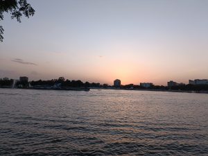 A tranquil waterfront scene during sunset, featuring calm water reflecting the soft hues of the sky.
