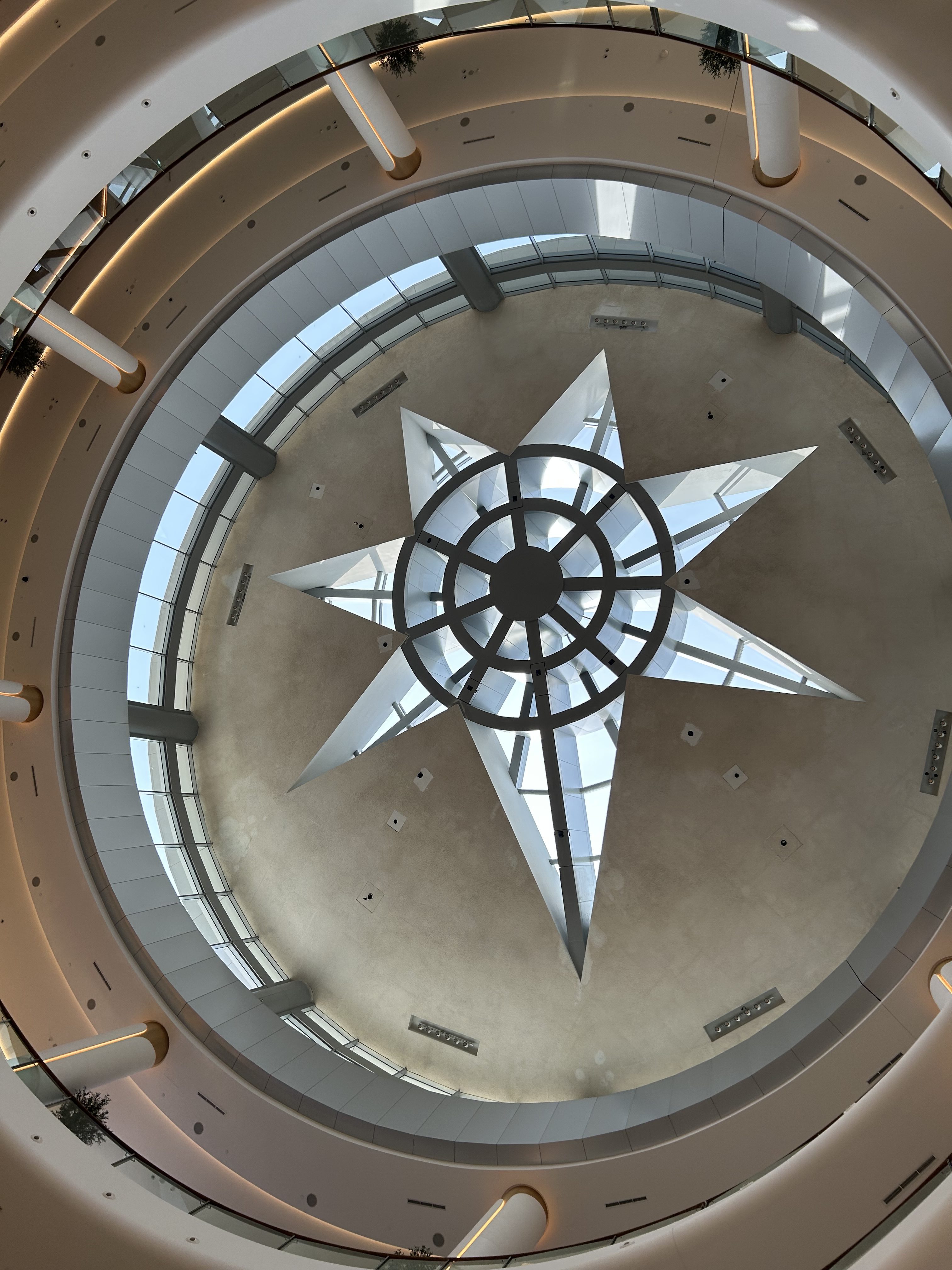 A view looking up at a modern architectural ceiling featuring a large, geometric star-shaped skylight at the center.