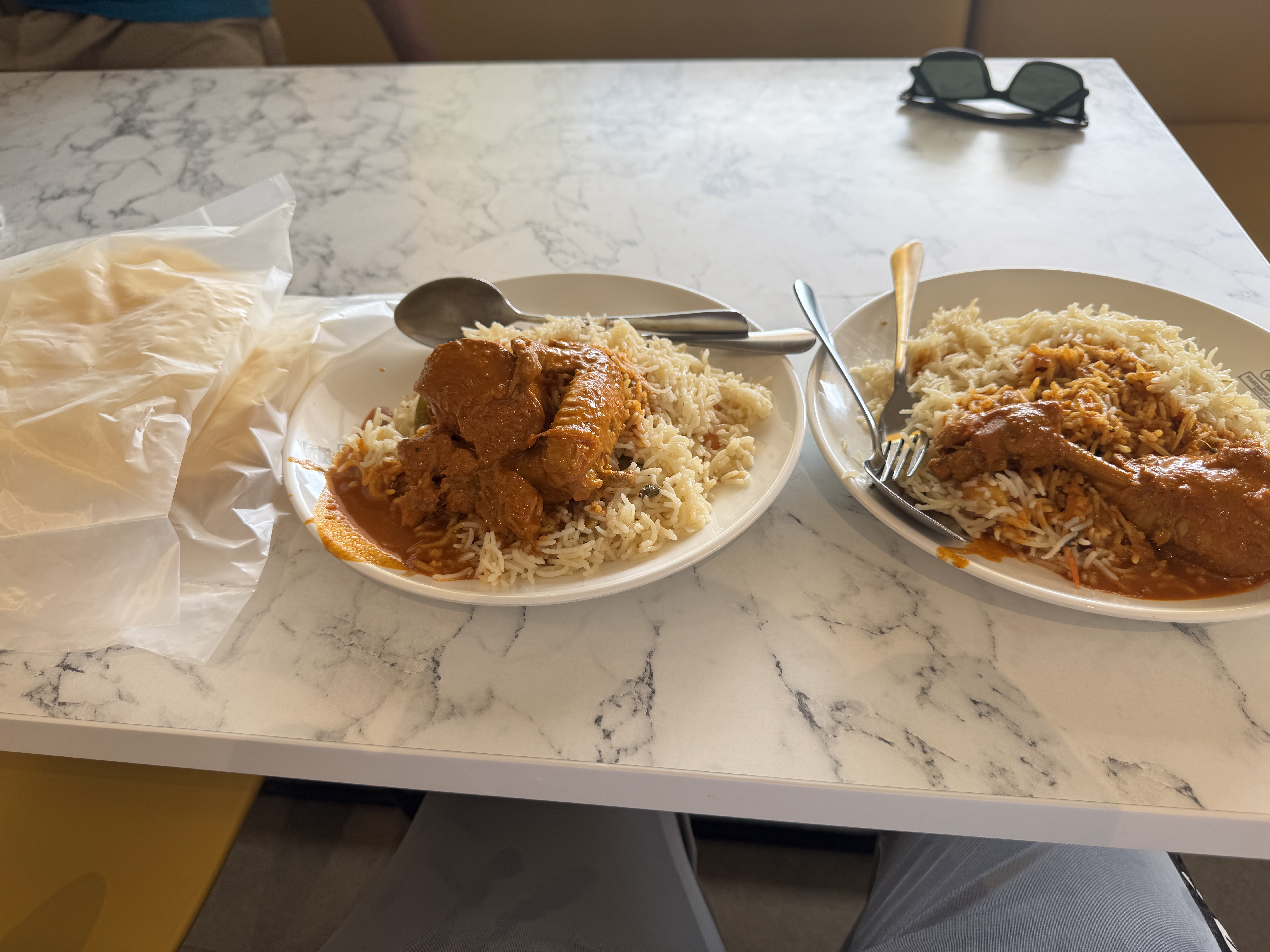 Two plates of rice with chicken served on a marble table.