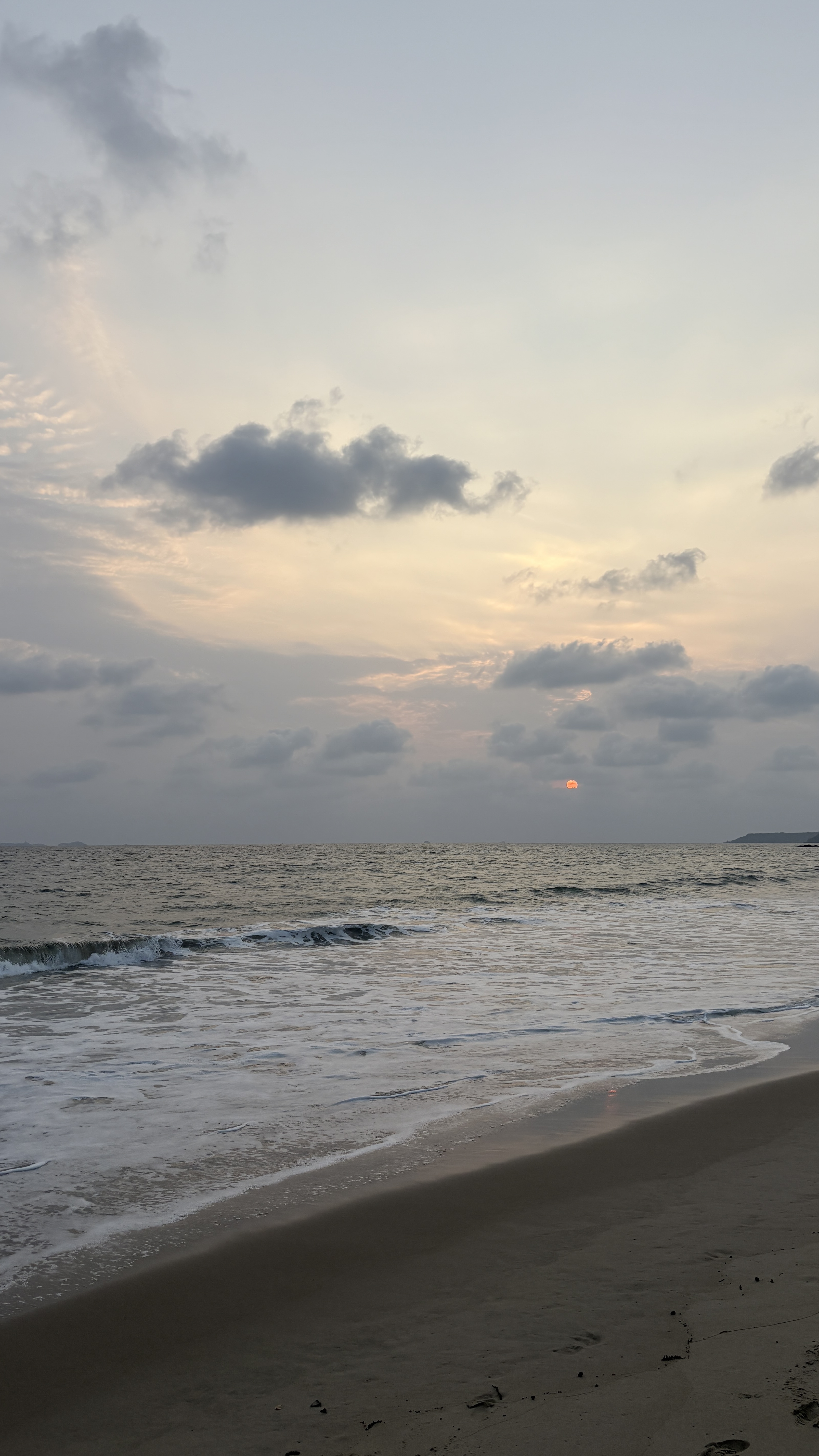 A serene beach at sunset, with soft waves gently lapping at the sandy shore.