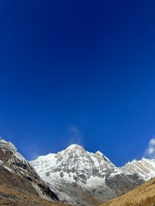 

A majestic Aanapurna basecamp mountain peak covered in snow rises against a clear blue sky.