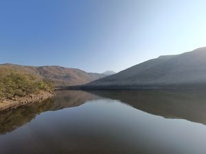 A serene landscape featuring a calm body of water reflecting the surrounding hills.
