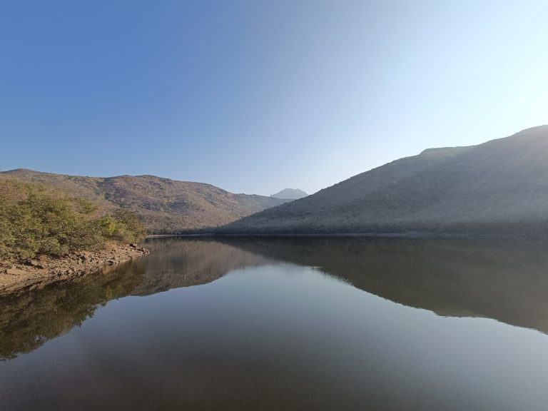 A serene landscape featuring a calm body of water reflecting the surrounding hills.