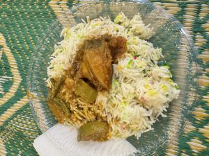 A plate of rice with chicken curry on a clear plastic plate.