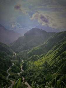 A panoramic view of lush green hills and valleys, with a winding river flowing through the landscape.