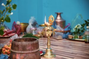 A brass oil lamp with a flame, adorned with decorative elements.
