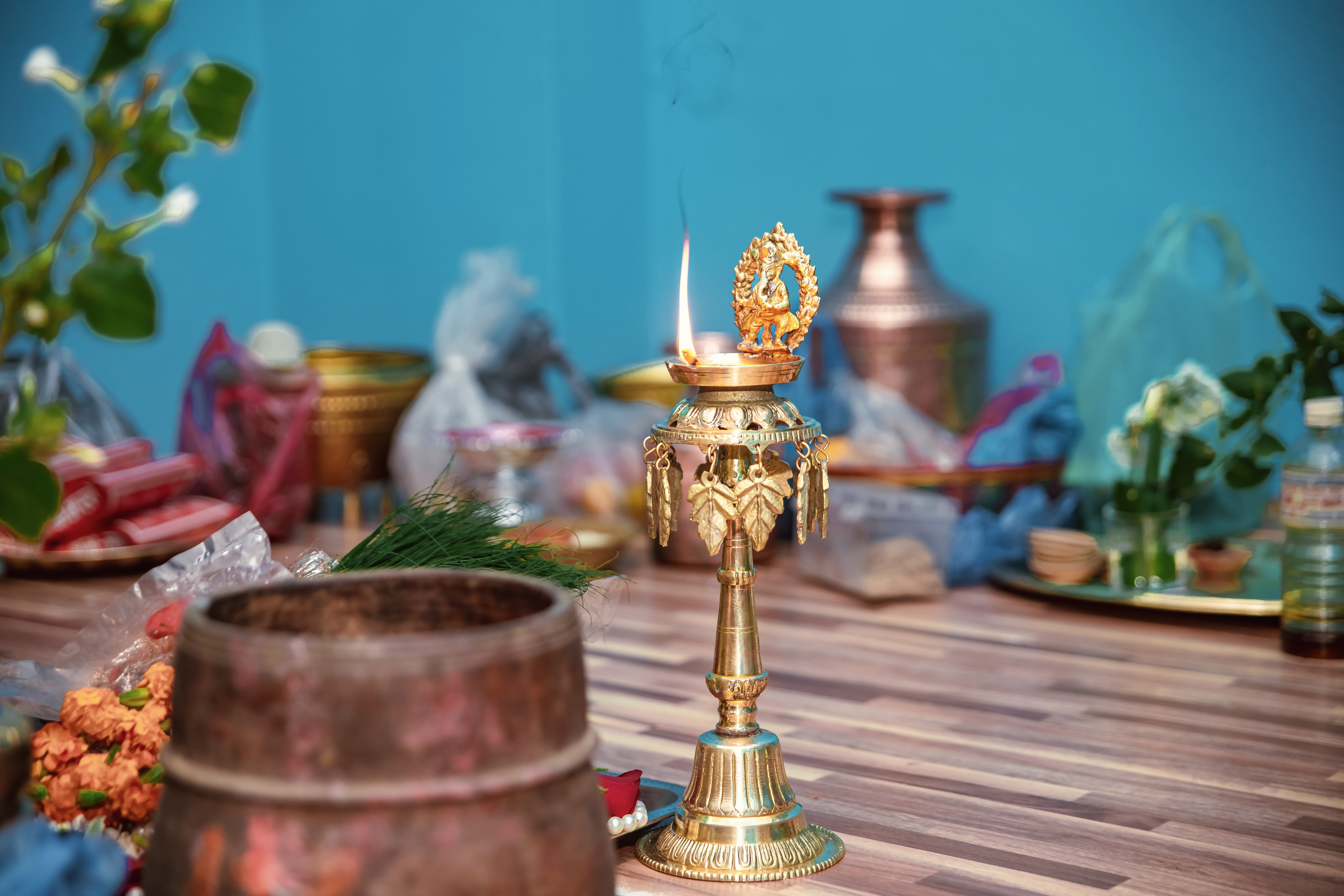 A brass oil lamp with a flame, adorned with decorative elements.