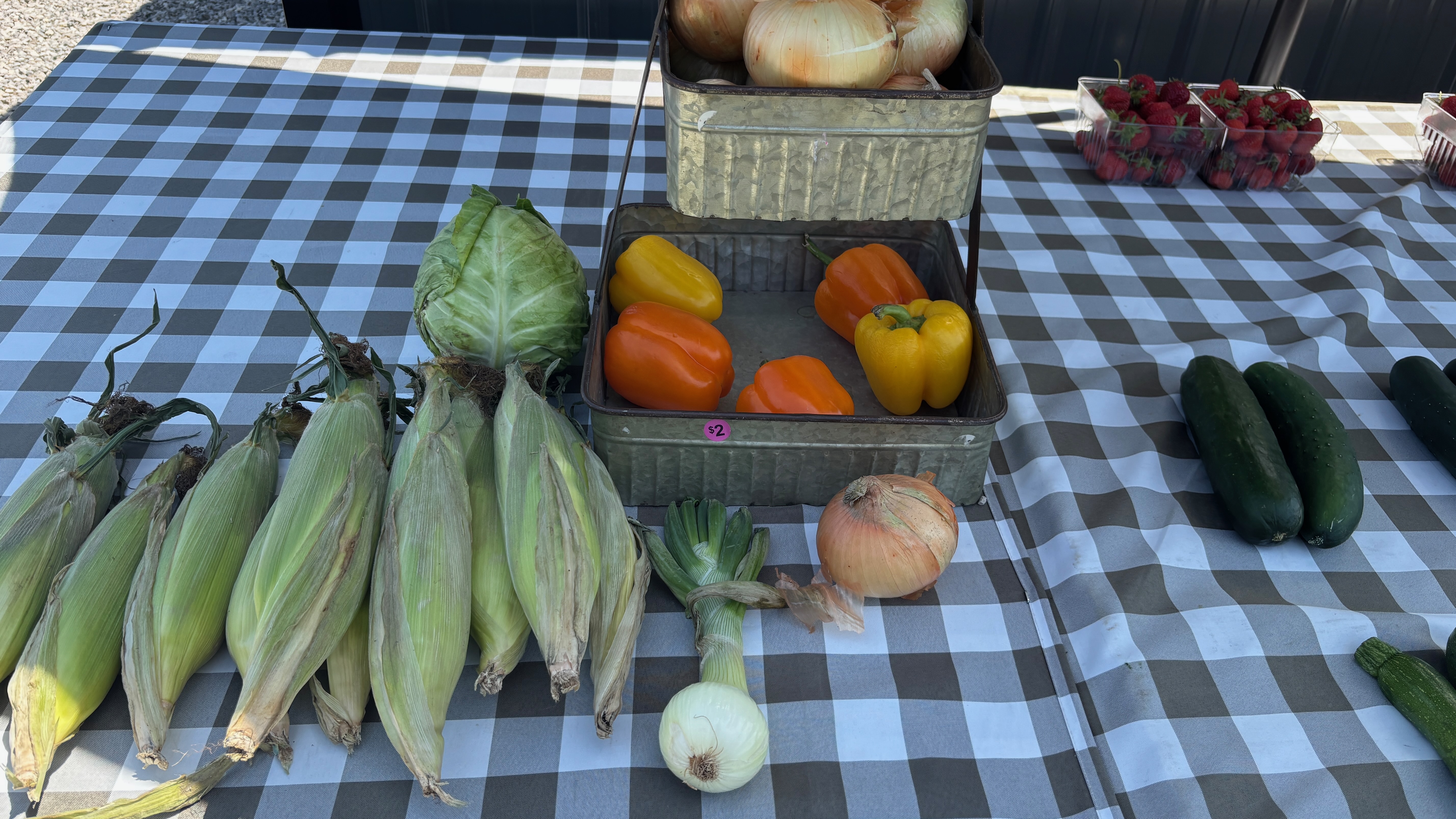 A table with various vegetables arrayed for sale.