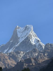
A snow-capped Machhapuchre mountain peak rises sharply against a clear blue sky. 