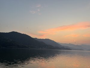 A serene lake scene at dusk, featuring tranquil waters that reflect the soft colors of the sunset.