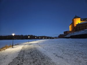 Snowy walkway with lit streetlights next to the Castle of Häme, Finland.