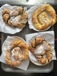 A delicious selection of Portuguese pastries, each golden and flaky with twisted layers, some filled with chocolate and others dusted with sugar or sprinkled with nuts—perfect companions to a morning coffee in Lisbon.