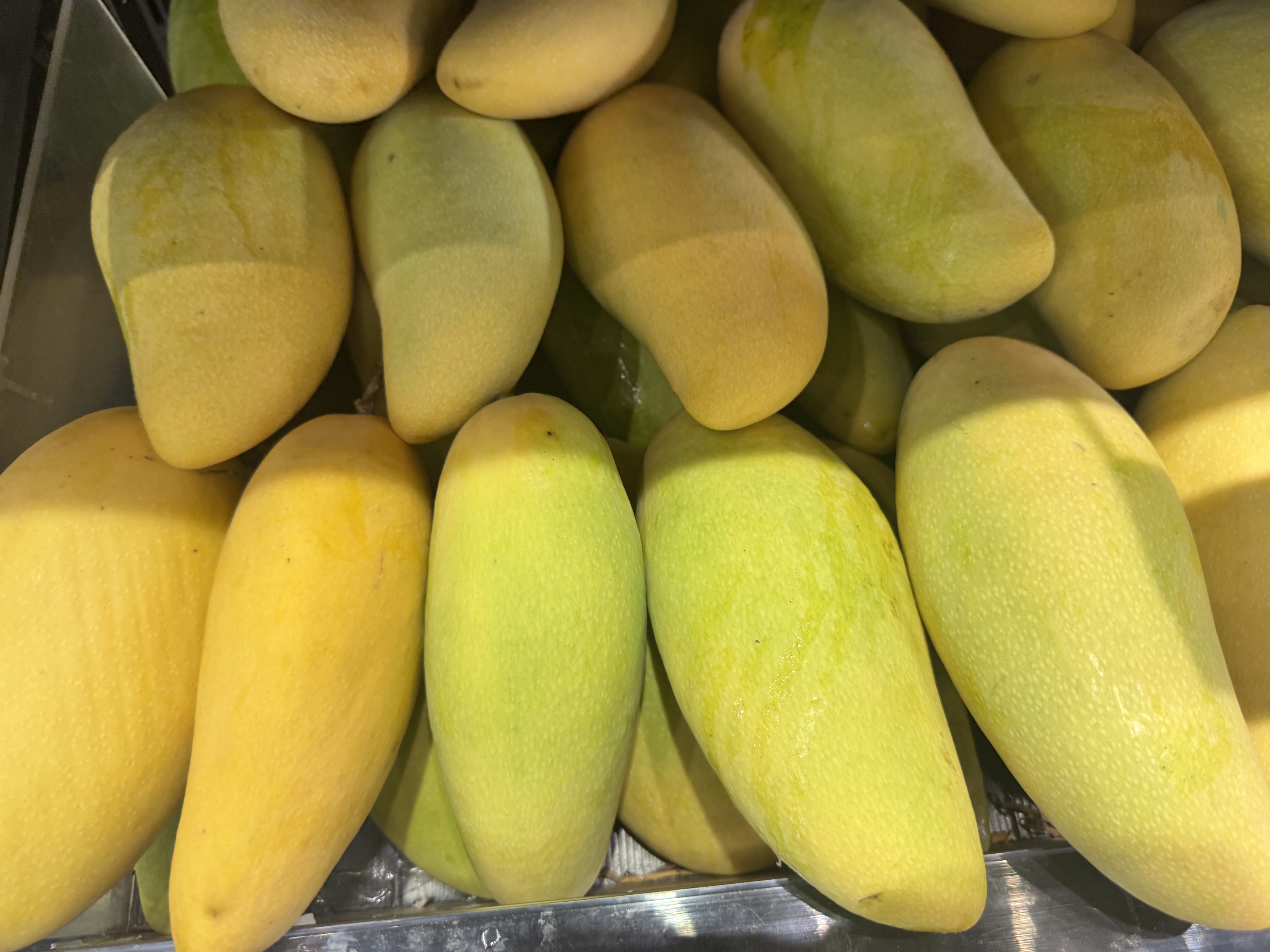 A bunch of yellow and light green mangoes in a fruit display.