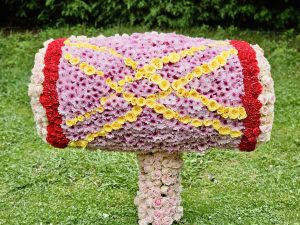This is a large floral sculpture shaped like a Mridangam, a traditional Indian percussion instrument. This creation features various flowers, including pink and red blooms forming the main body and yellow flowers arranged in a decorative pattern. It was arranged as part of the famous Ooty Flower Show.