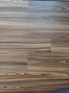 A close-up view of a wooden floor featuring a pattern of light and dark brown shades with a smooth, polished texture. 